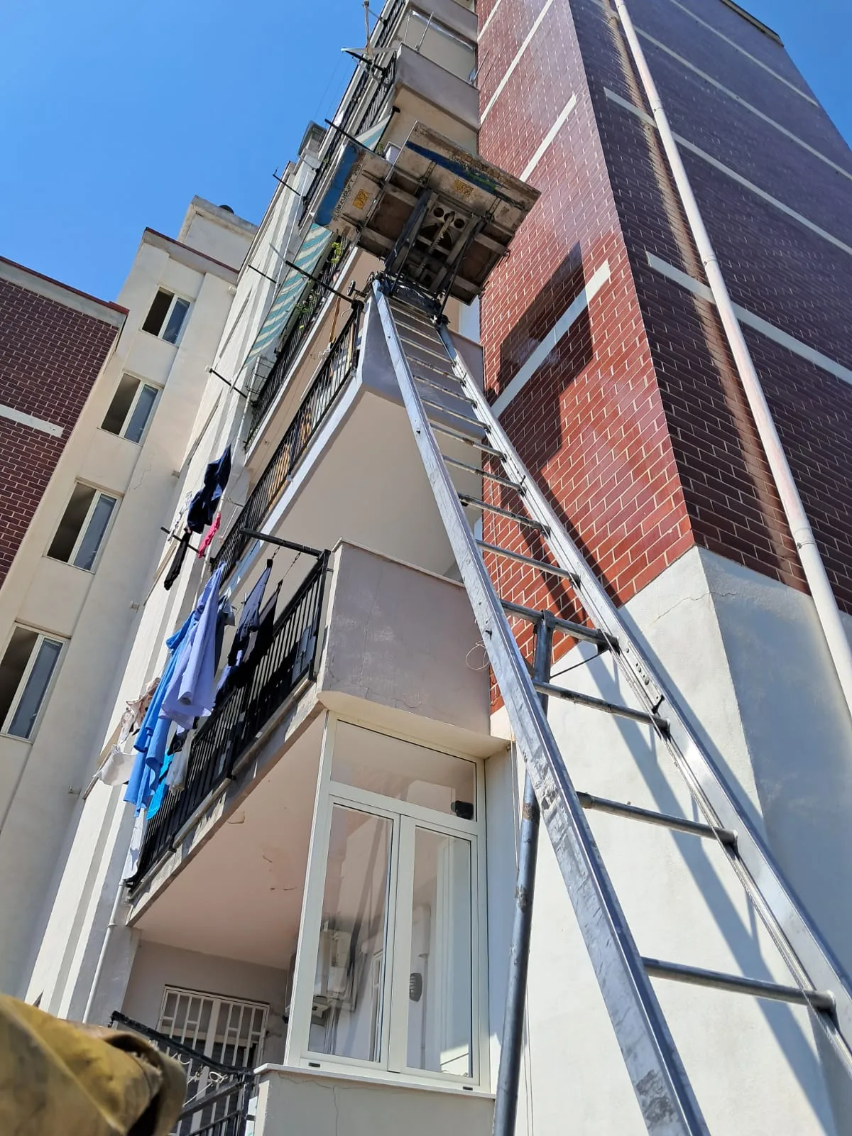 Scala elevatrice appoggiata alla facciata, con la piattaforma ferma davanti al balcone del quarto piano